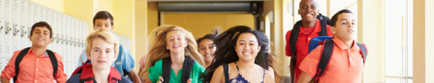 Diverse group of young high school students run down a school hallway lined with lockers.